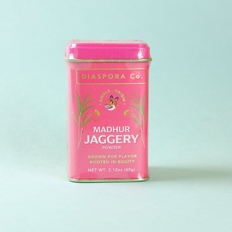 Pink canister of Diaspora Co. Madhur Jaggery on a light blue background