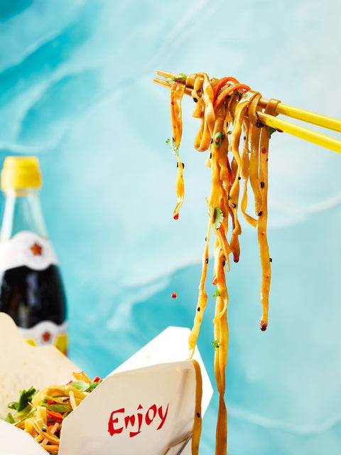 Soy Sauce noodles on chopsticks with a takeout box and Gold Plum Chinkiang Black Vinegar