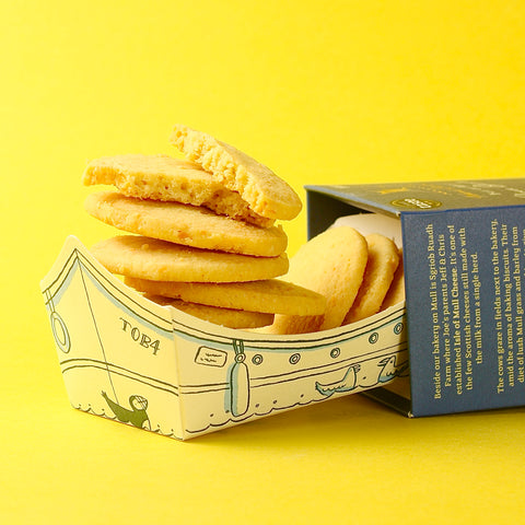 Stack of Isle of Mull Farmhouse Cheddar Biscuits  in a decorative box on a yellow background