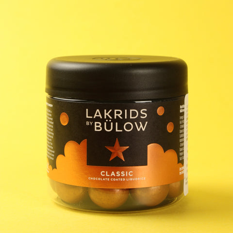 Jar of Lakrids by Bülow Chocolate Coated Licorice on a yellow background