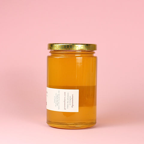 A jar of Lost Meadows Honey on a pink background right side label.